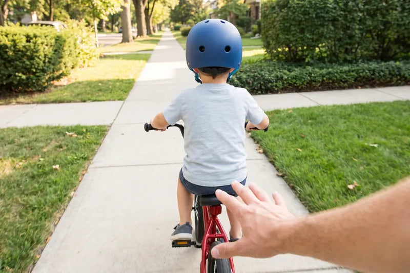 Letting go of a child's bike seat as they ride off, seen from the parent's eyes
